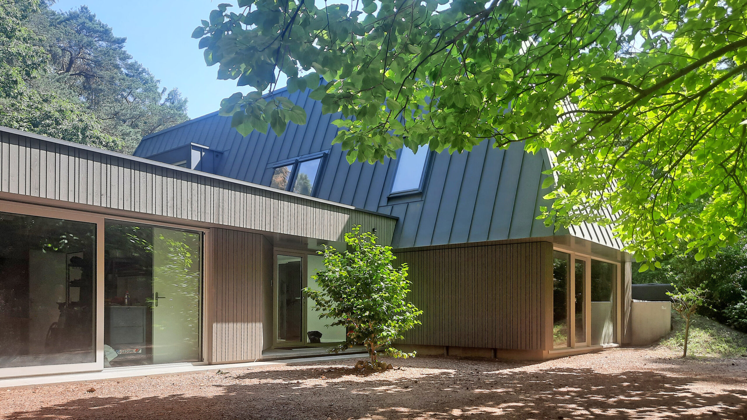 Voorkant villa met golfplaten, houten delen, bomen