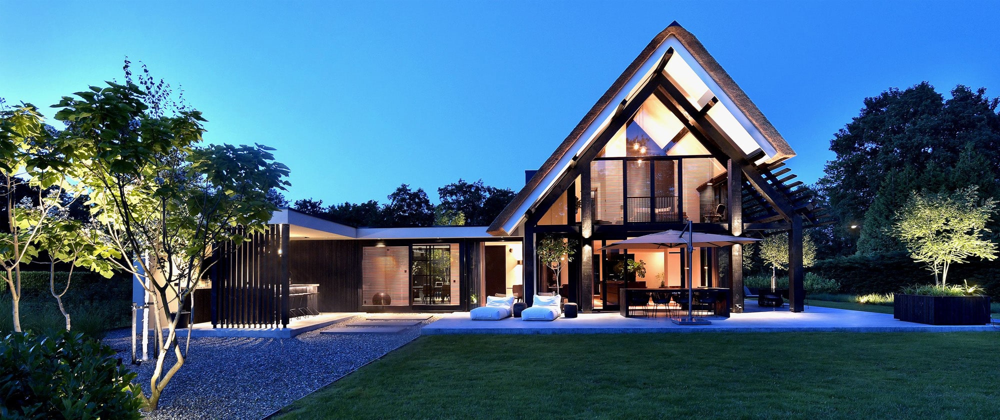 Voorgevel villa met pannendak, zwart-wit gevelopstelling en tuinverlichting