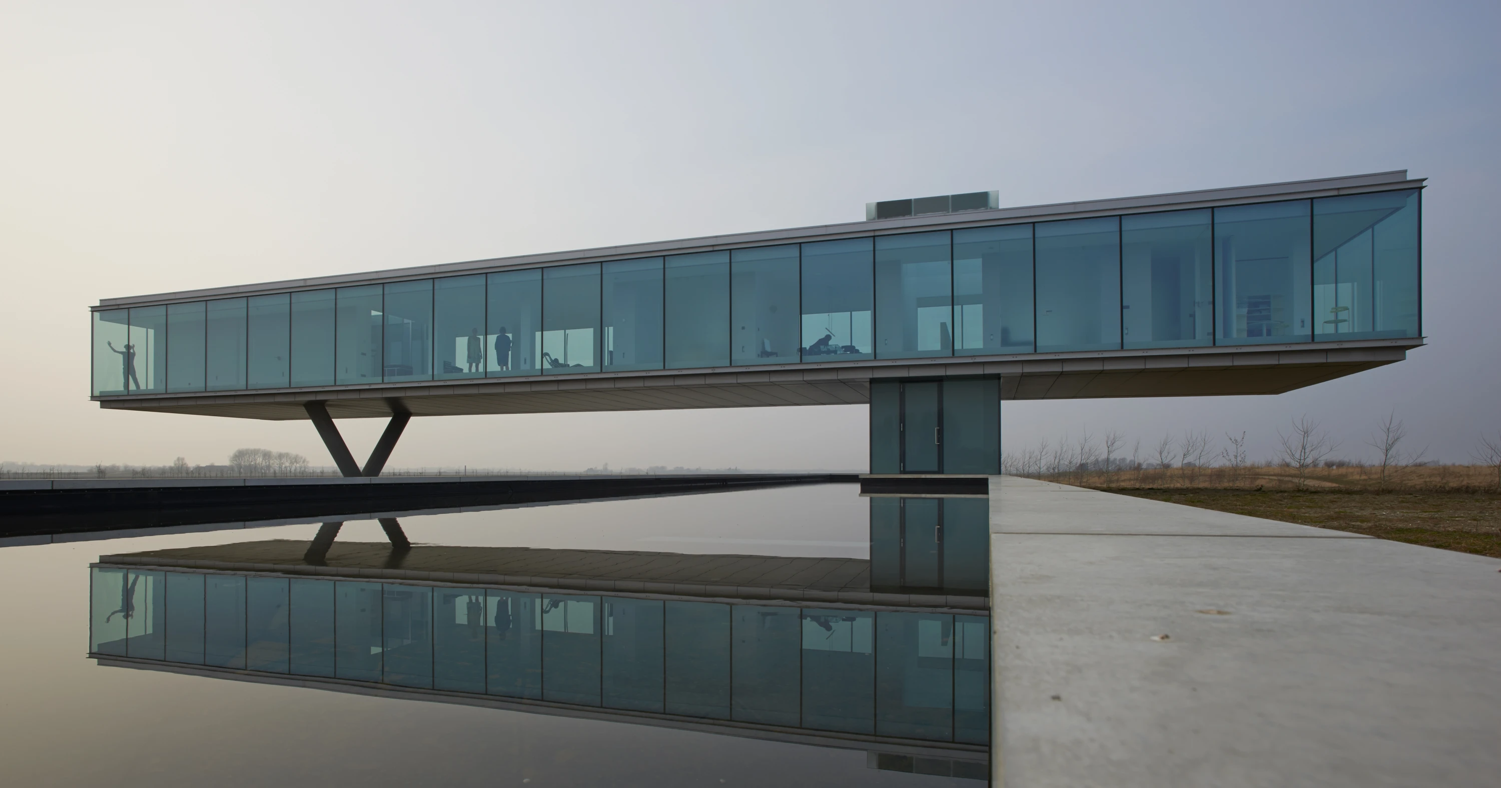 Moderne villa met glazen gevel, betonnen steun en ondergrondse garage met auto