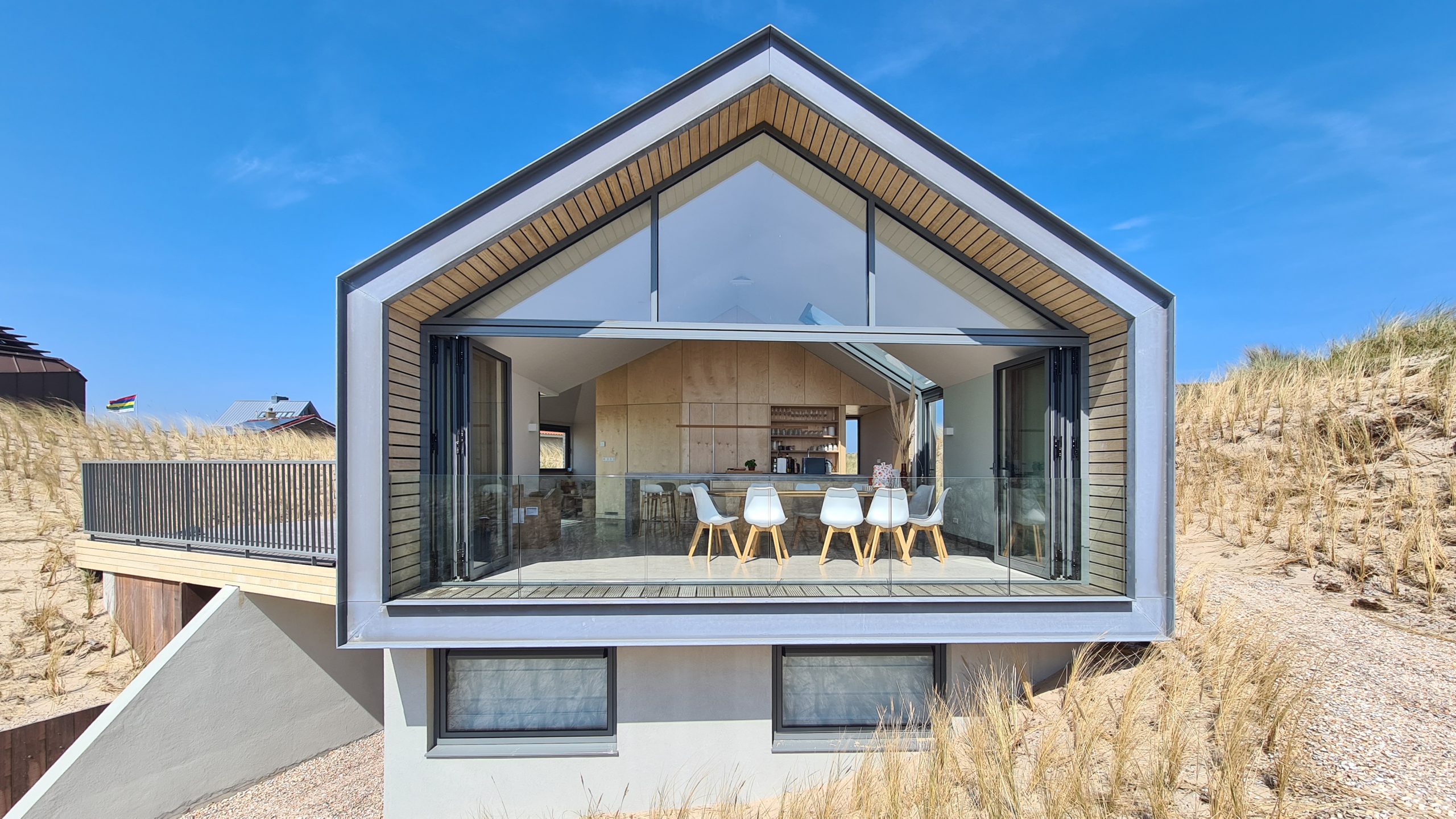 Open living space met grote glazen voorgevel en houten plafondafwerking