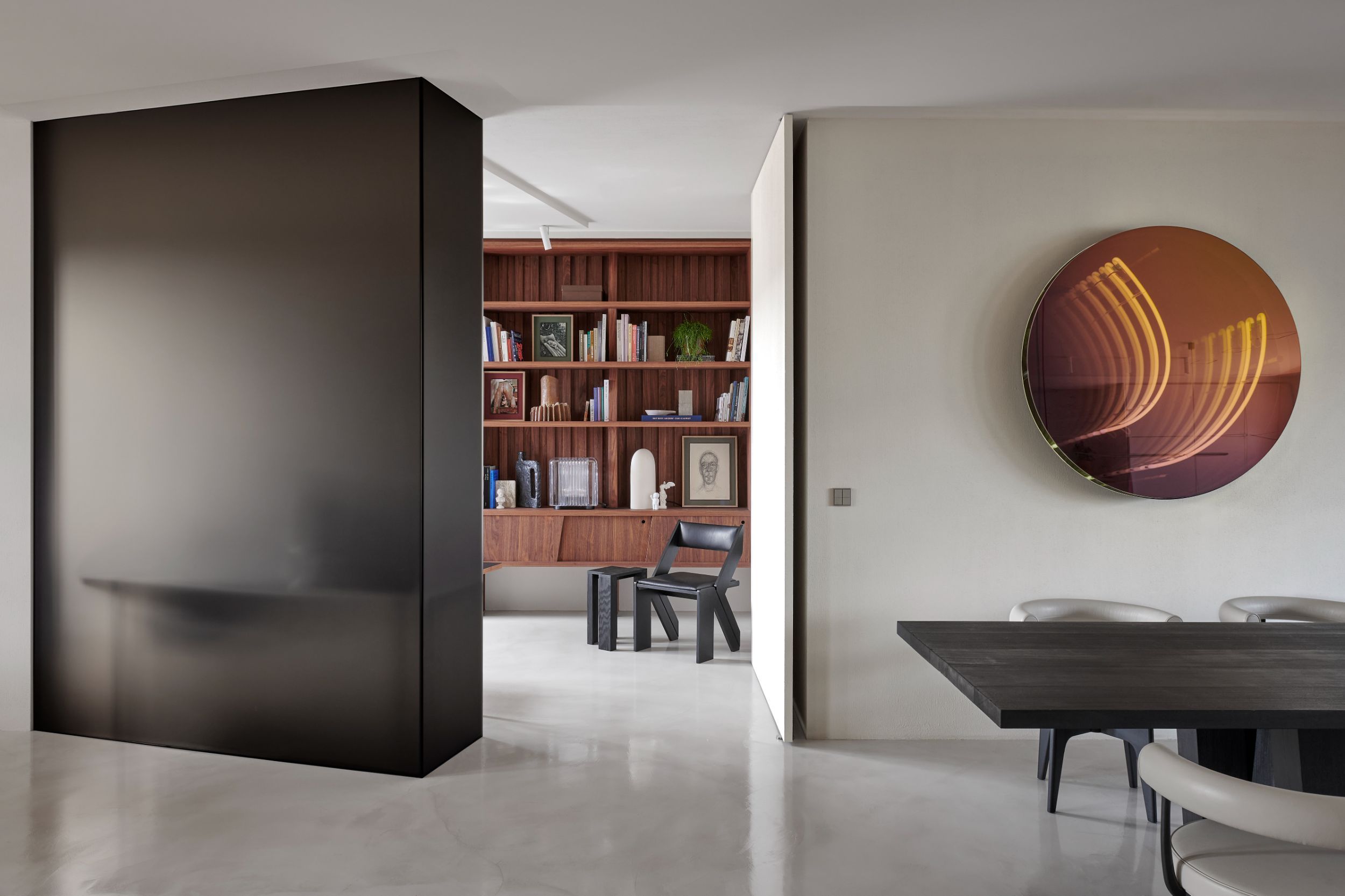 Eetkamer met zwarte tafel, witte stoelen en koperen wandkunst
