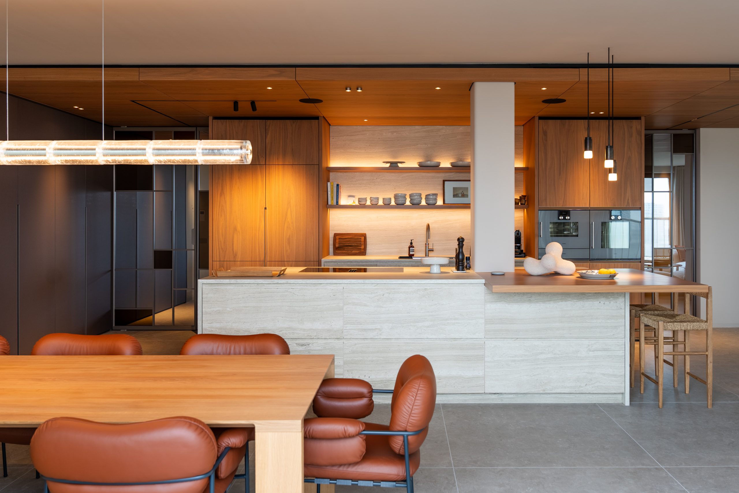 Open keuken met wit keukeneiland en houten kasten, terracotta stoelen