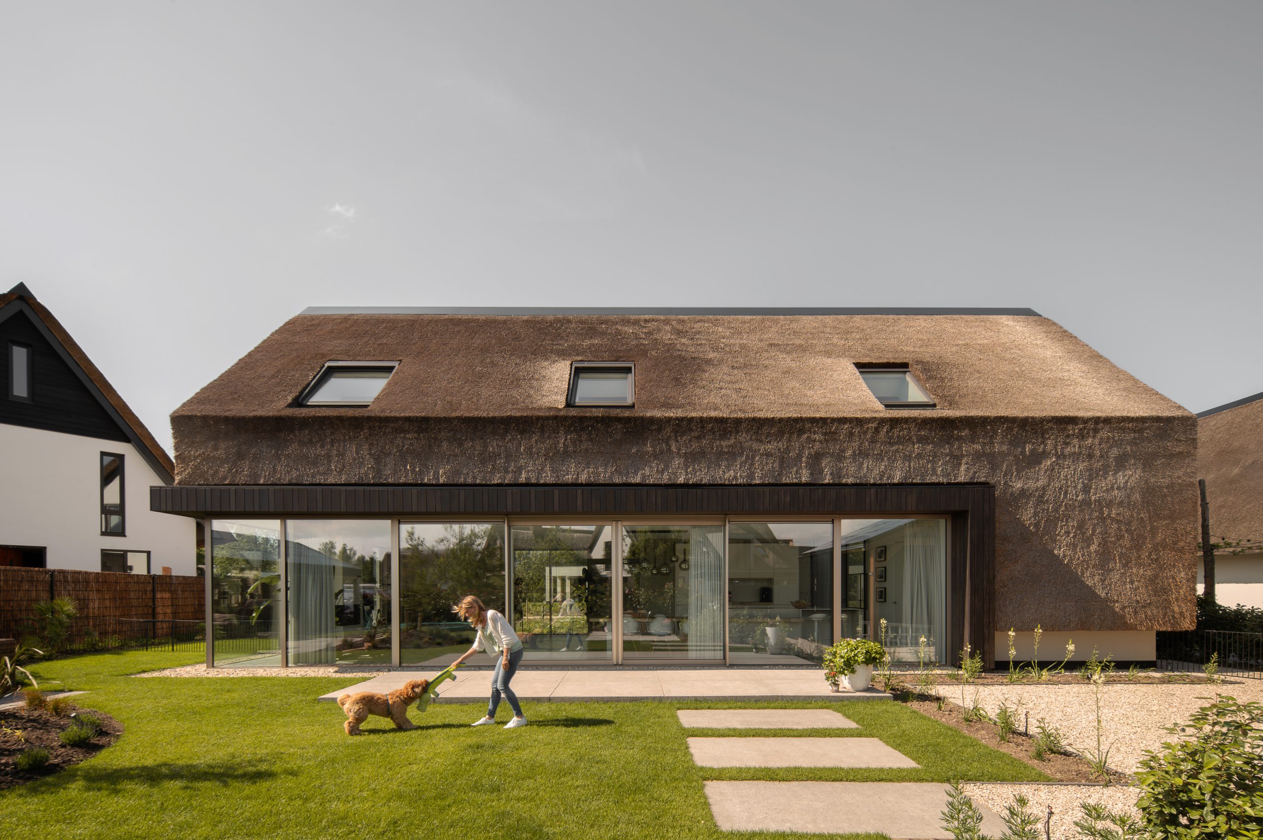 Rietgedekt huis met staande houten gevelframing en volle glazen voorgevel