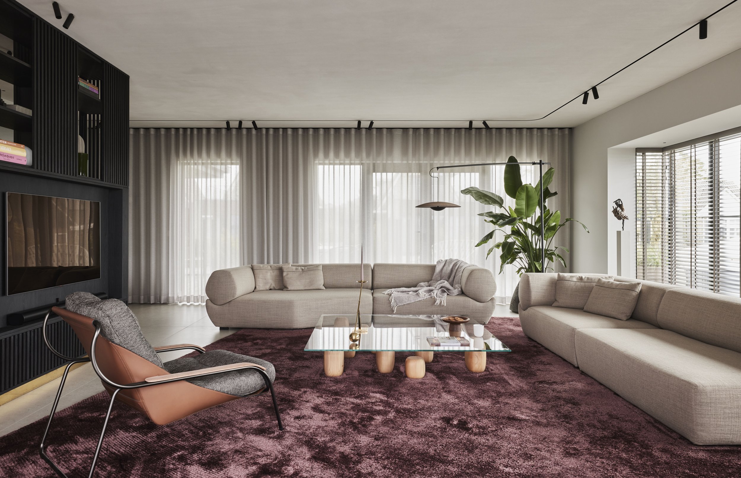 Woonkamer met beige modulaire bank, aubergine vloerkleed en zwart tv-meubel
