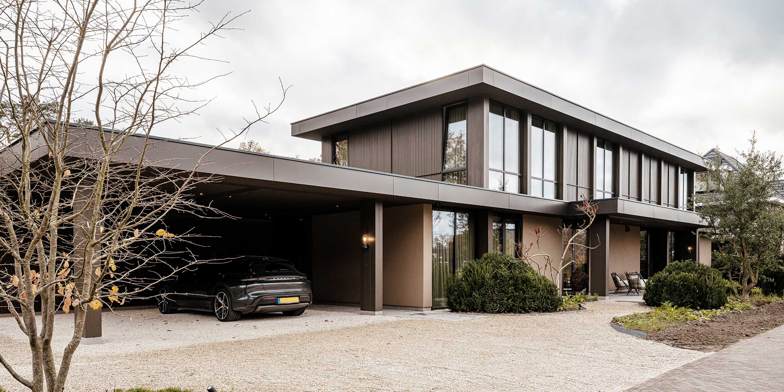 Villa voorgevel met garage, donkerbruine baksteenwanden en metalen carport