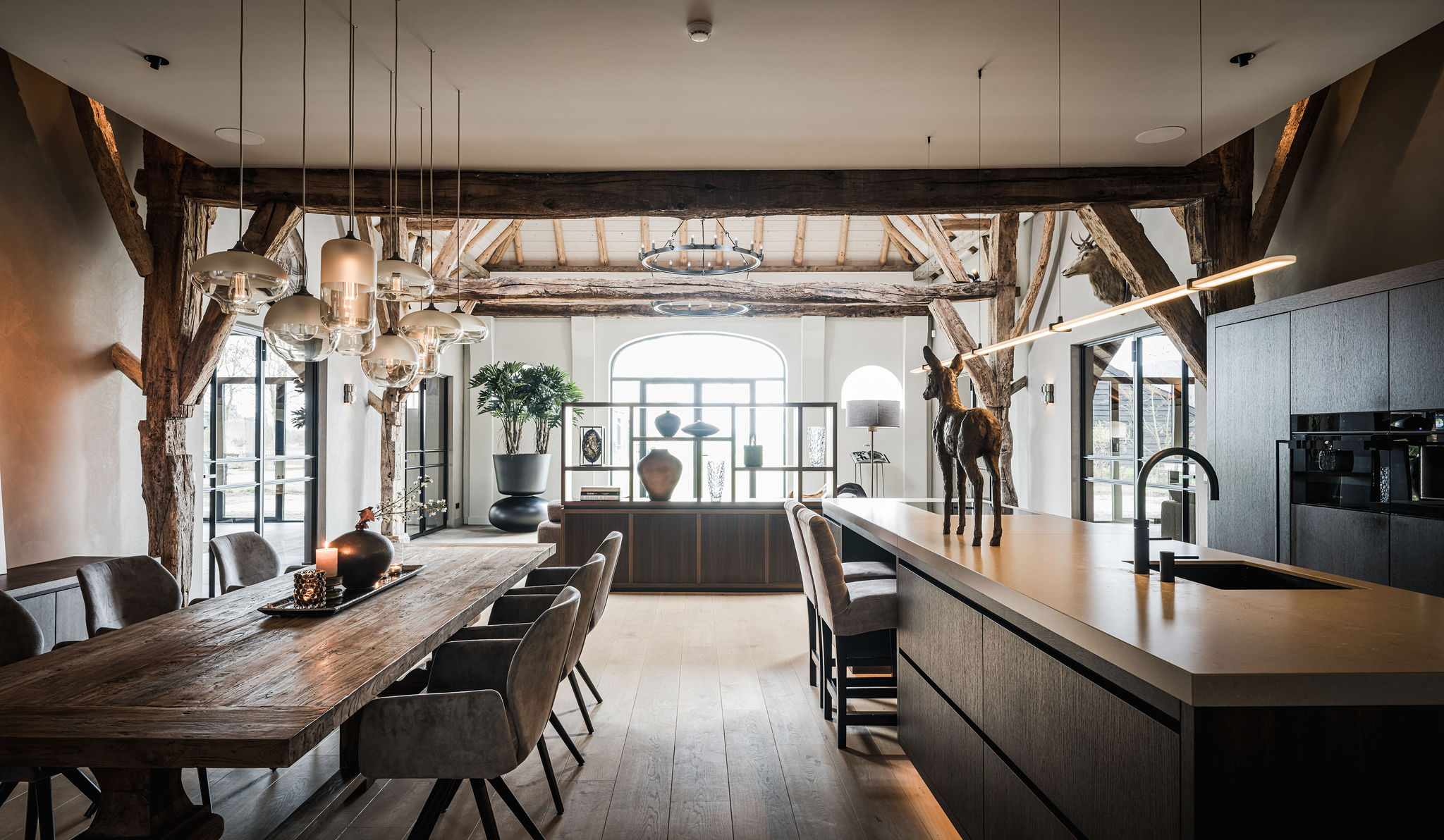 Keuken-eetkamer met donkere kastenwand, houten balken en stalen raamwerk