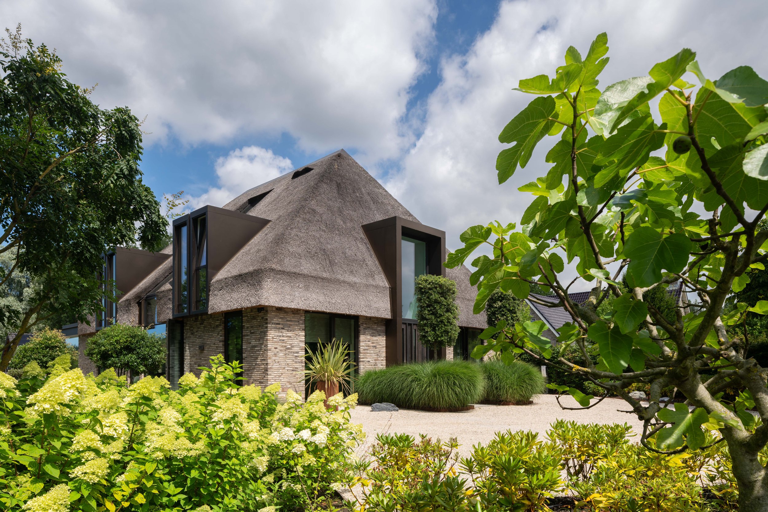 Rietgedekte villa met bakstenen sokkel en moderne glaswanden