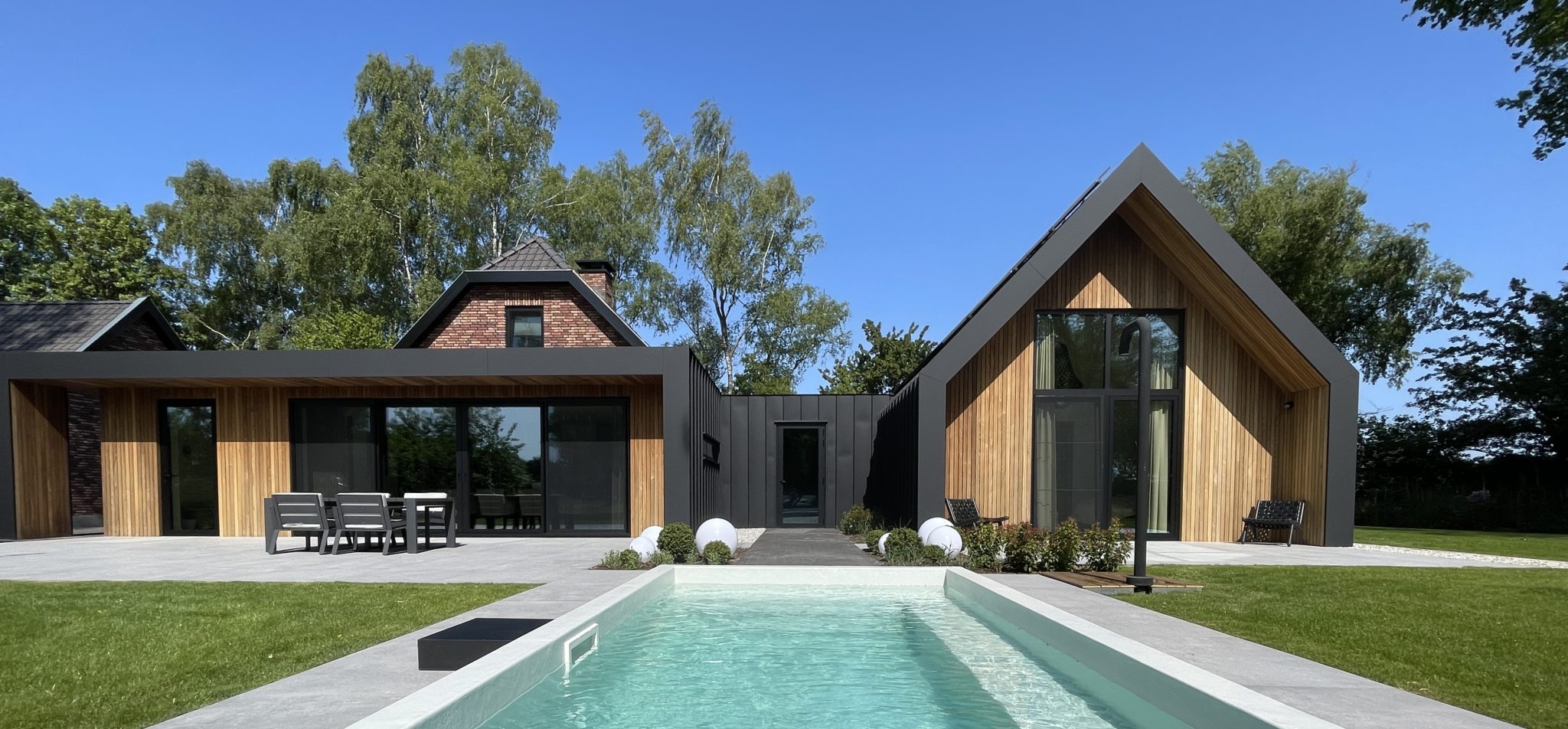 Moderne villa met houten en zwarte gevelbekleding, zweefbad en gazon