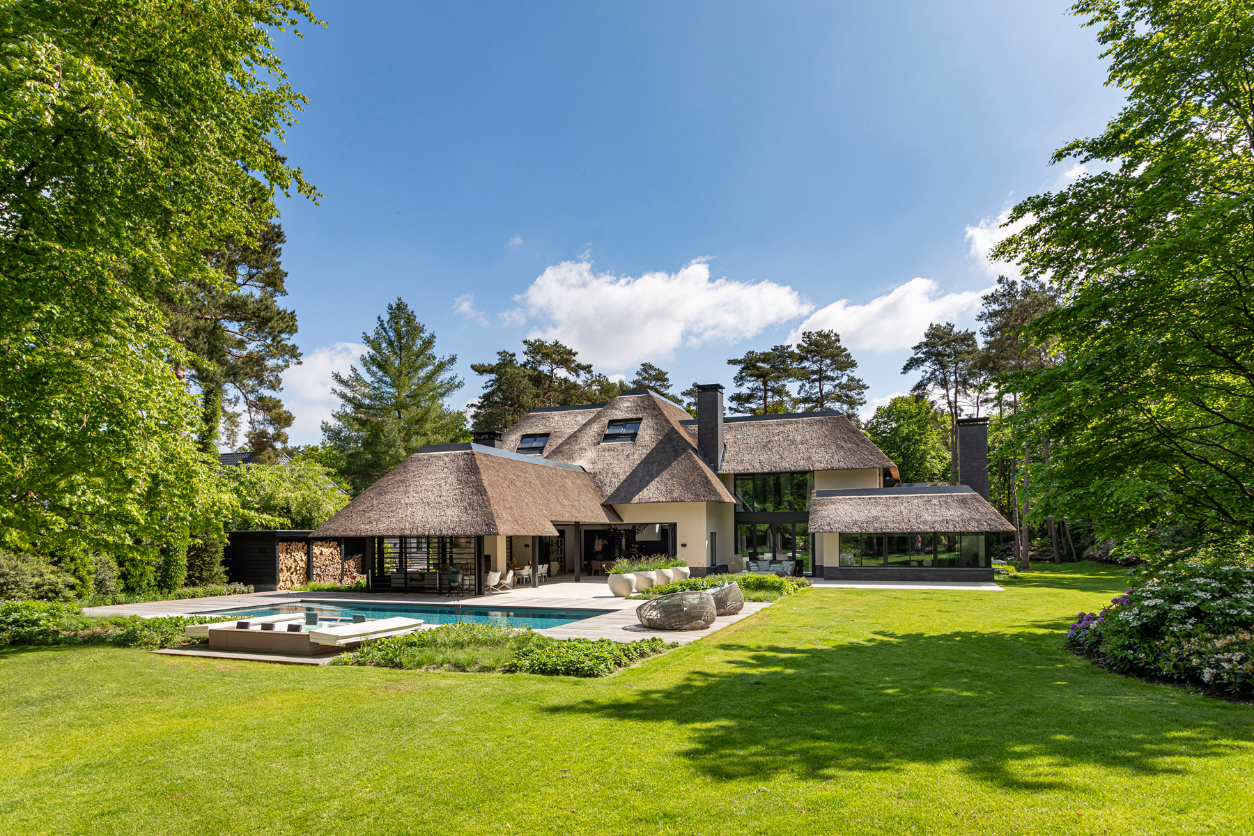 Achtergevel villa met rieten dak, zwembad en grasveld