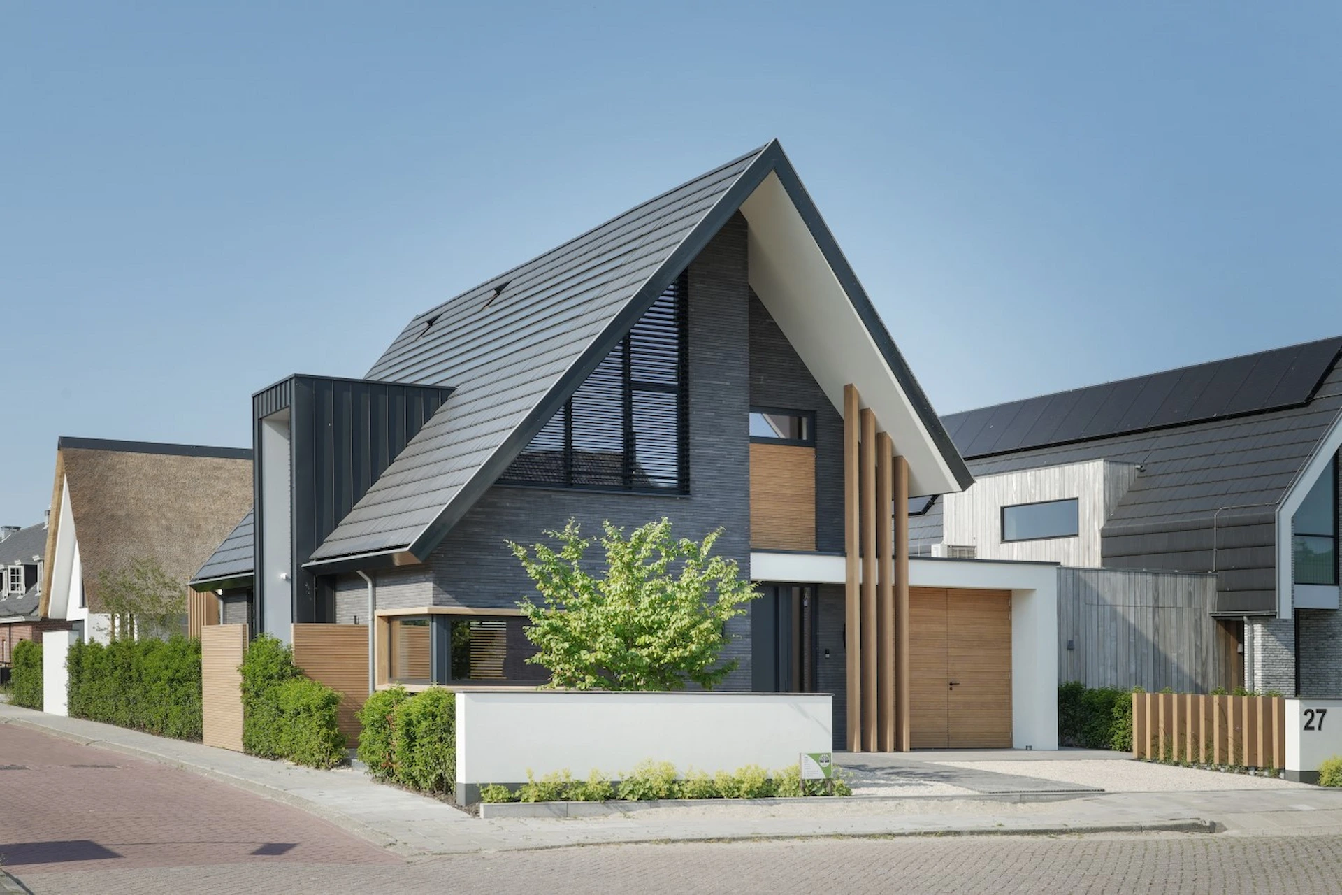 Voorkant woning met donkere gevel, houten accenten en metalen dak