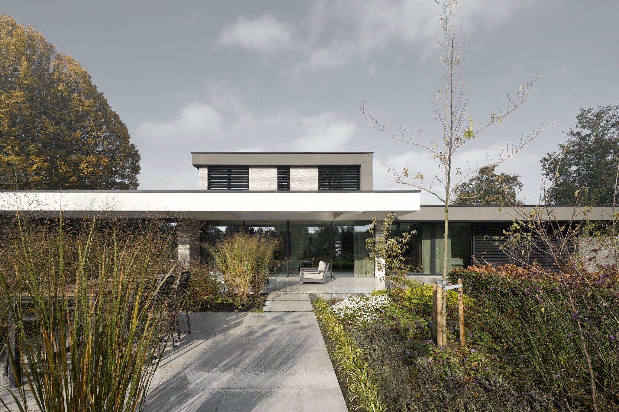 Moderne villa met wit stucwerk, brede terras en decoratieve grassen