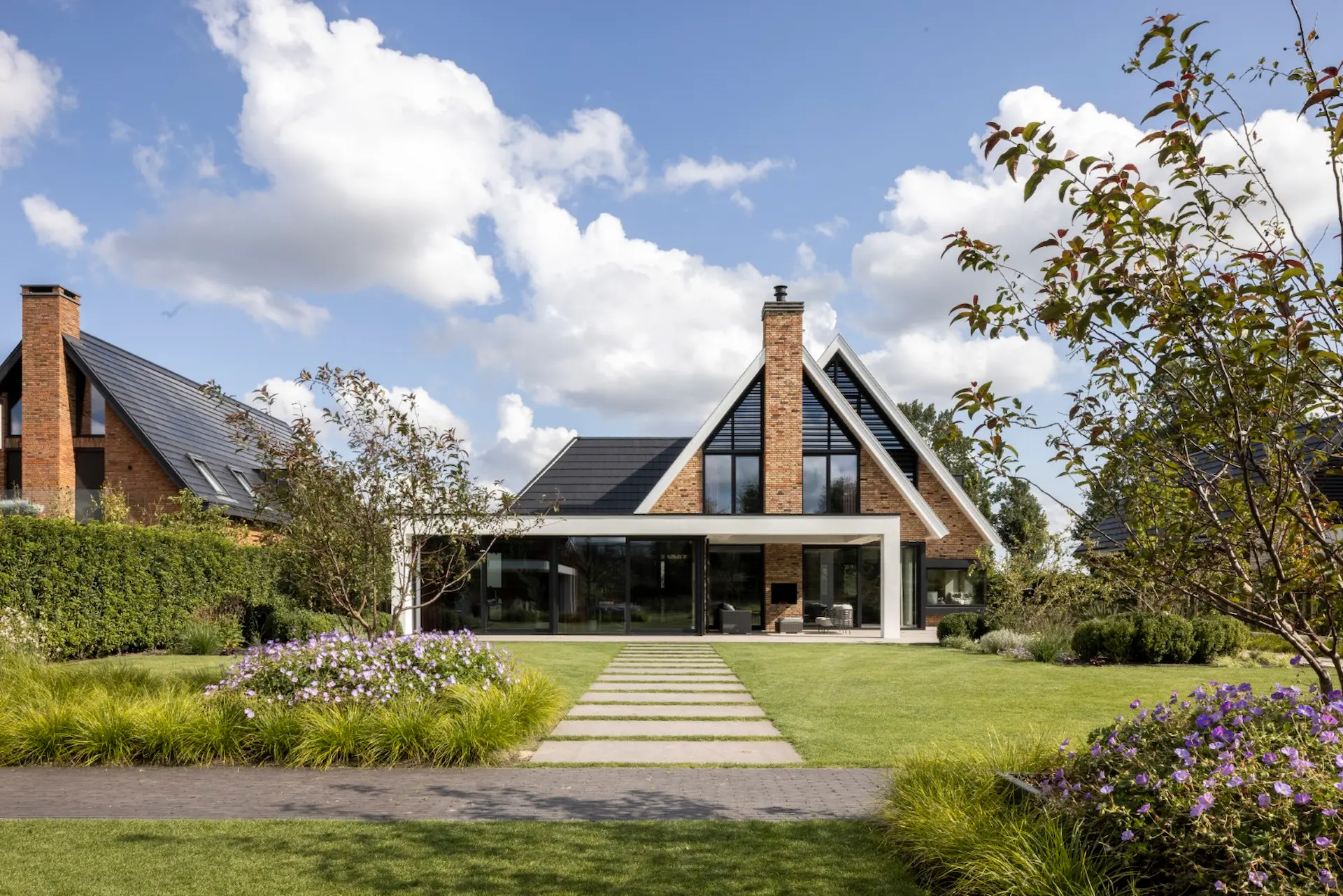 Moderne villa met bakstenen gevels, donkere dak en brede grasveld