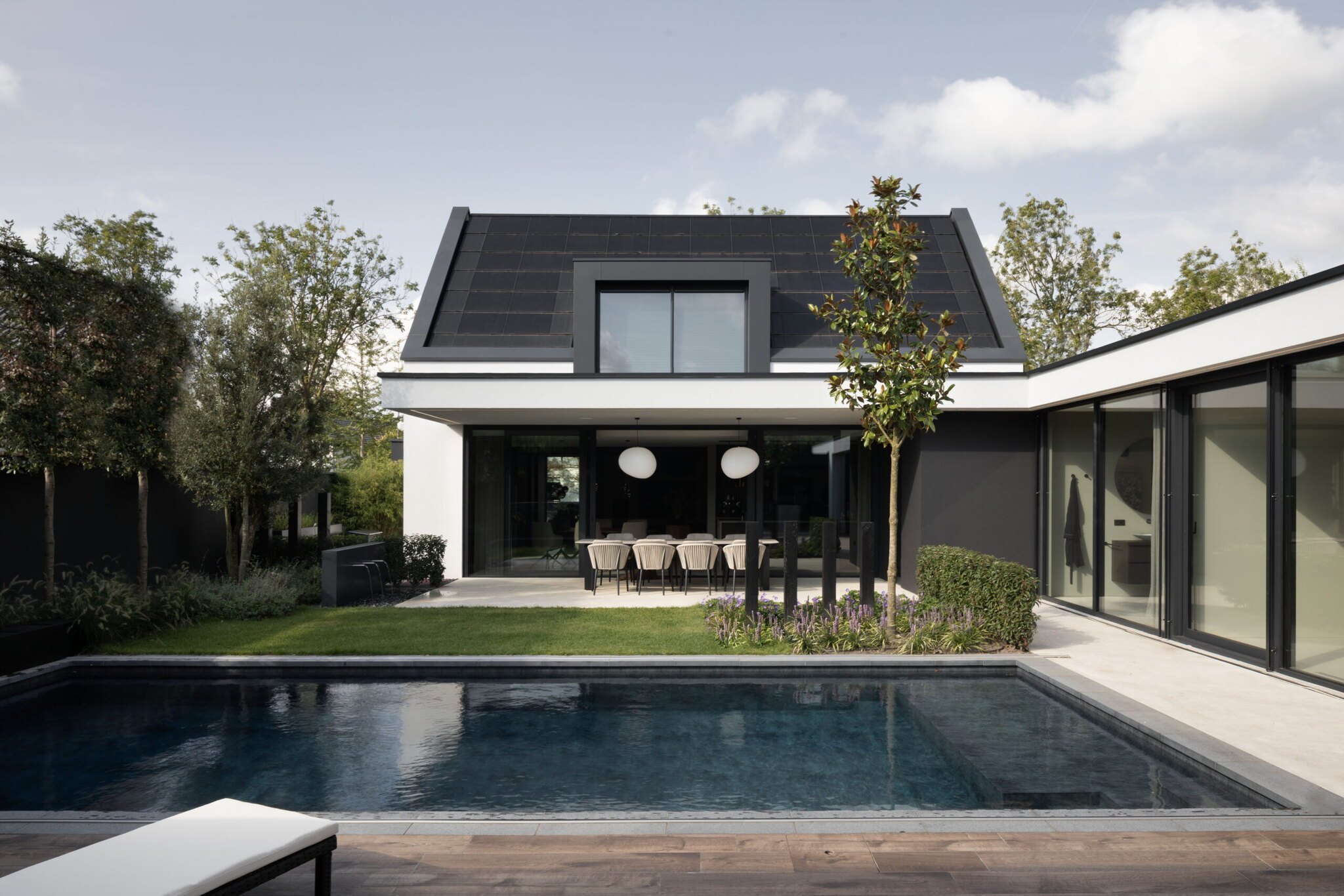 Moderne villa met zwart dak, witte gevel en zwembad op voorgrond