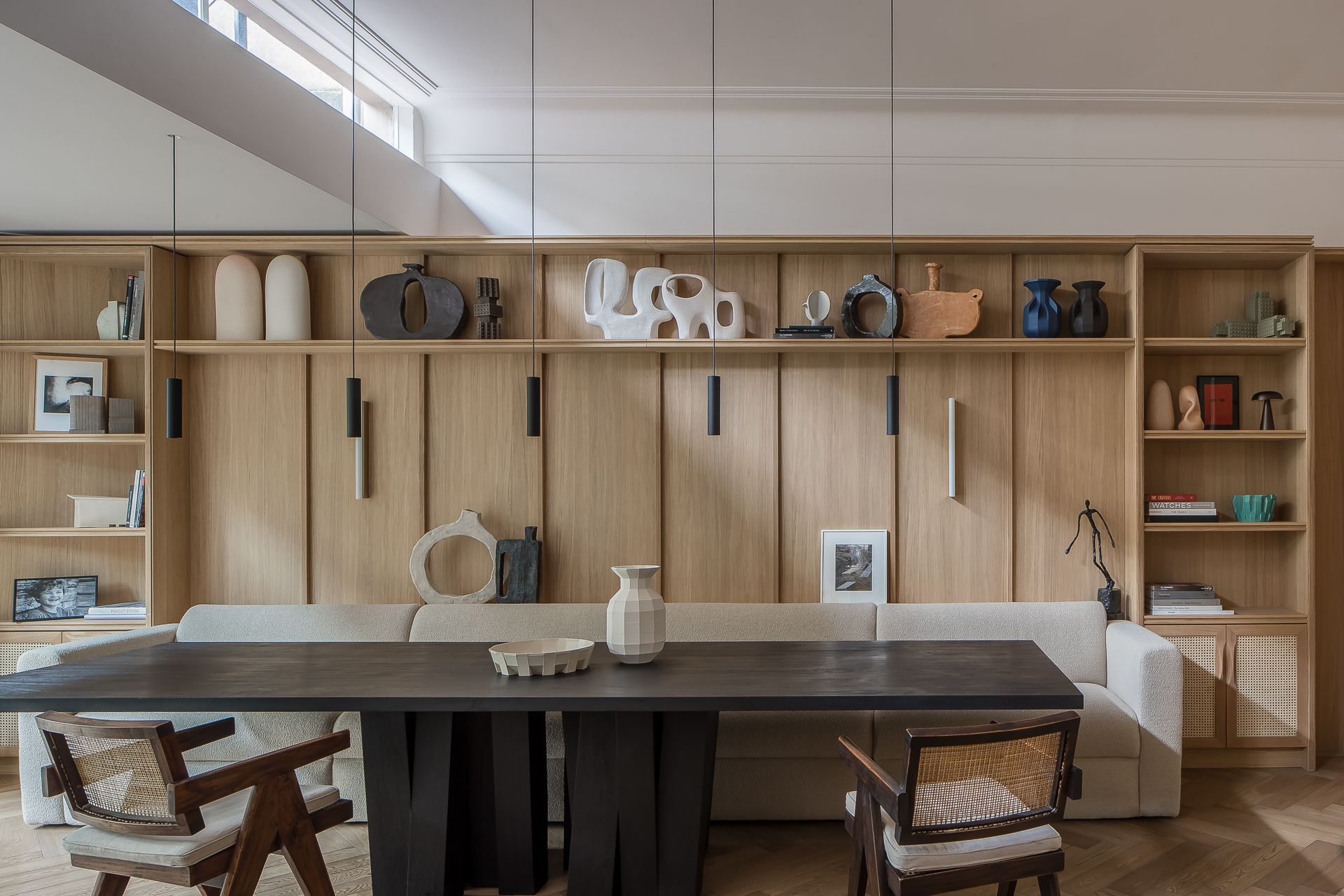 Eetkamer met zwart tafelblad, eikenhouten kastenwand en rieten stoelen